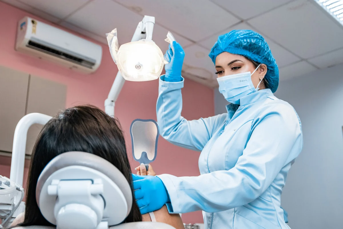 Una dentista visita una paziente sulla poltrona odontoiatrica
